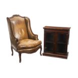 LIBRARY FURNITURE A leather covered wingback chair, together with an antique book shelf cabinet with