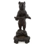 GERMAN BLACK FOREST UMBRELLA STAND An antique carved bear umbrella stand with a metal basin.