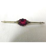 An Art Deco styled precious metal bar Brooch with centre rectangular Ruby (measuring approximately