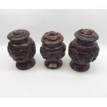 A collection of three Chinese Carved Hardwood Lidded Containers of baluster form, all decorated with