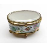 A European Porcelain Small Oval Dressing Table Casket with gilt mounts and hinged glass top, the