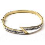 High grade precious metal hollow bangle of cross-over design set with white stones stamped “18ct”