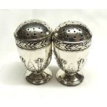 A pair of late Victorian Vase-shaped Silver Pepper Casters, with foliate embossed decoration,