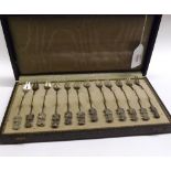 A cased set of twelve Eastern white metal novelty Forks, each with a finial modelled as a dancing