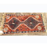 A small 20th Century Prayer Rug, decorated with geometric shapes in blue and red, 2’9” x 1’5”