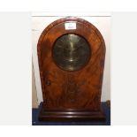 A Walnut cased Mantel Clock, the arched case with plinth base and hinged door carved with an