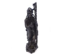 A large Oriental Hardwood Figure of a wise man clutching a staff in one hand and the neck of an