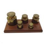 Graduated set of five Brass weights from 500 to 50gms on a fitted hardwood stand