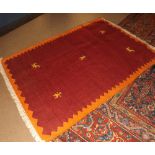 20th Century wool rug, with geometric animal designs on a mainly red/orange field, 5  7  x 4