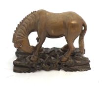 An Oriental Carved Hardwood Model of a Horse, the head inset with glass or composition