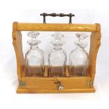 20th Century Oak framed three-bottle Tantalus of typical form, 14" high
