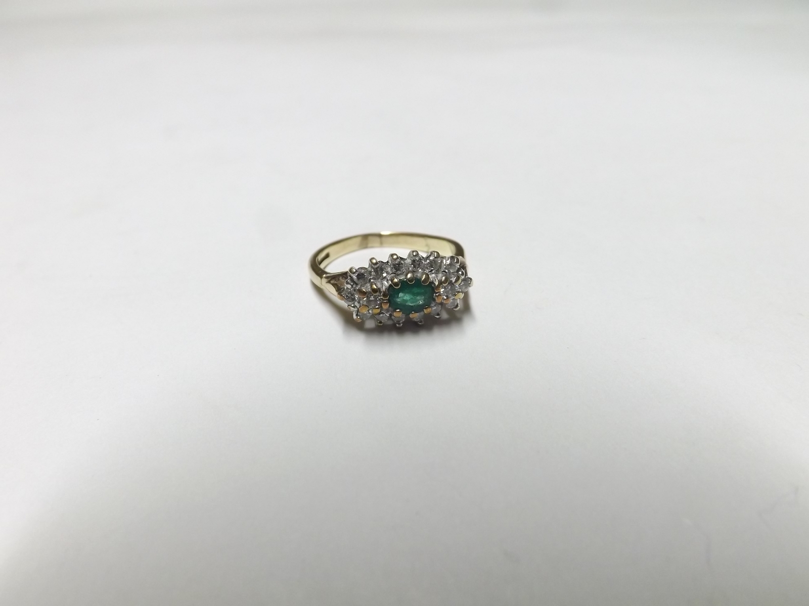 Hallmarked 9ct Gold Ring featuring a centre oval Emerald surrounded by small Brilliant Cut Diamonds