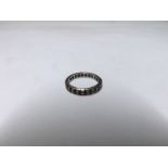 Unmarked precious metal small red stone set eternity Ring