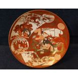 A Kutani Circular Dish of tapering form, typically decorated in iron red with panels of figures etc,