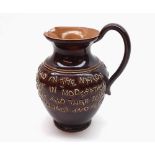 A Doulton Lambeth Stoneware Motto Jug decorated with lines of text on a brown background, 6" high