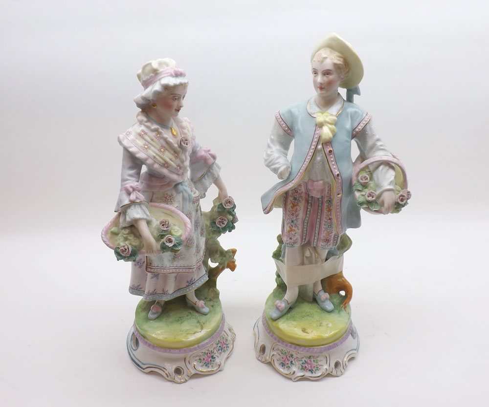 A pair of late 19th Century Continental Figures of lady and gent in period dress, raised on circular