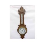 A late 19th Century Oak Cased Aneroid Wheel Barometer, the carved foliate case set with a