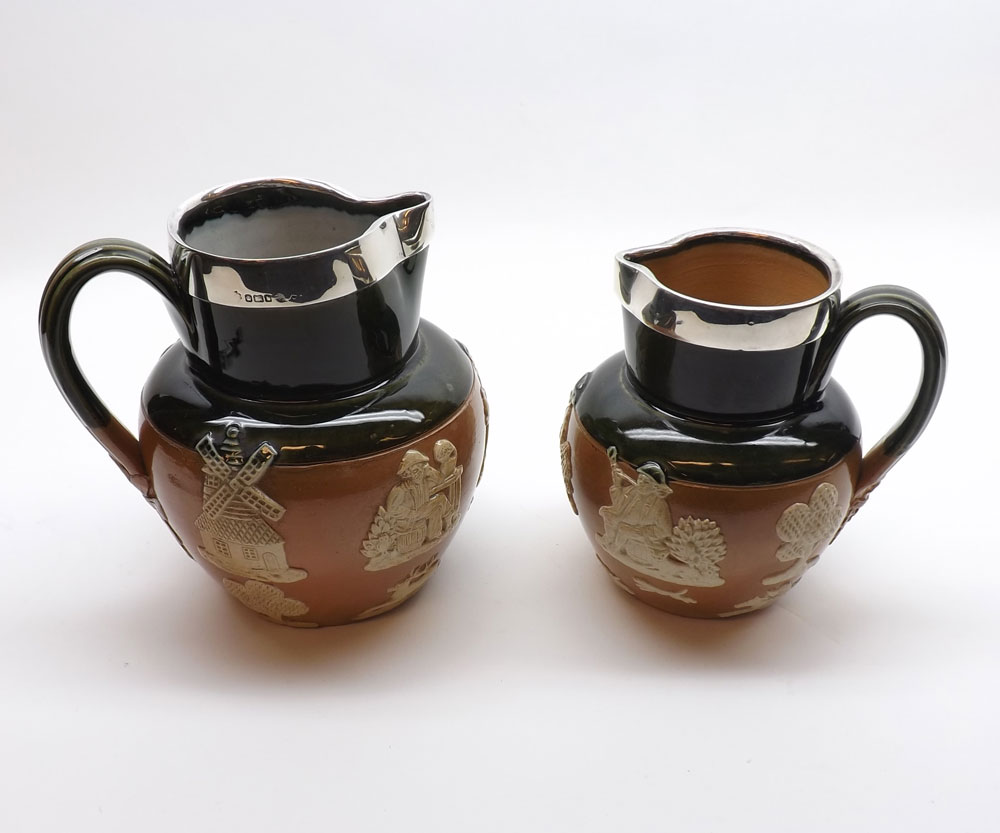 Two Royal Doulton Stoneware Jugs decorated with raised sprigs and fitted with hallmarked Silver