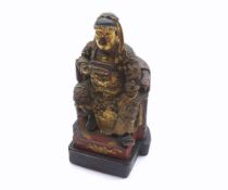 A Chinese Carved Hardwood Figure of a seated warlord on his throne, decorated throughout with gilded