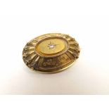 A Victorian oval Gold Brooch in Etruscan style, the raised centre featuring a small rose cut