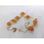 A yellow metal Amber Coloured Agate Bead Necklace with yellow metal spacers, stamped "9ct"