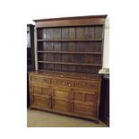 An Oak Dresser, plain plate rack back, the base with three frieze drawers over two panelled doors