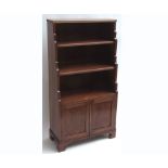 A Regency style Waterfall small Bookcase, three shelves over panelled doors enclosing cupboard on