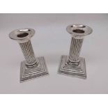 A pair of late Victorian Dressing Table Candlesticks, Silver encased, beaded and stepped loaded