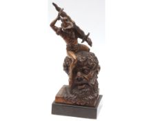 Unusual carved fruitwood model of a figure with oversized sword astride a bearded man’s head, signed
