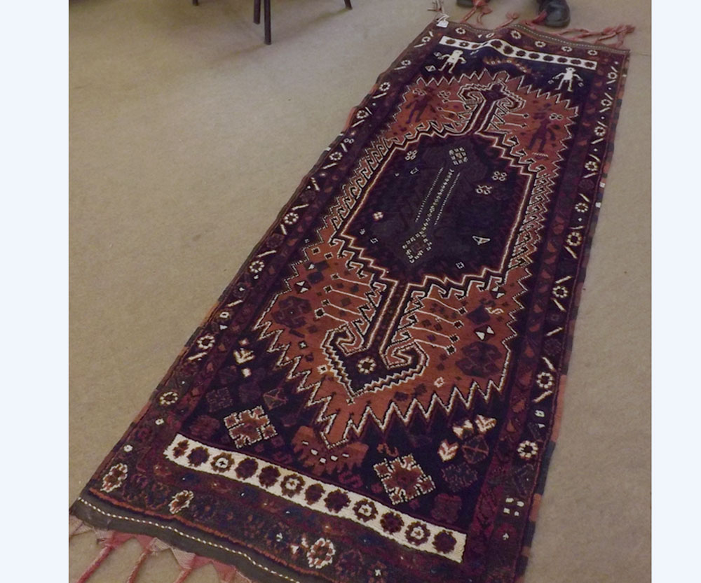A Caucasian Wool Runner, with central geometric panel, mainly dark blue and rust field, 6’10” x 2’8”
