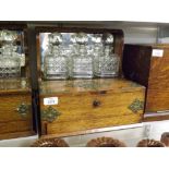 An early 20th Century Oak Tantalus, fitted with three decanters before a mirror back, with two