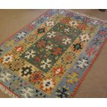 A Kilim Rug, predominantly decorated with geometric cruciform and other designs, on a green, pale