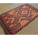 A Kilim Rug, decorated with geometric lozenges on a mainly pink field with black borders, 6’ x 3’4”