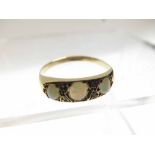 Unmarked yellow metal Ring in Edwardian style set with three small oval Opals interspersed by four