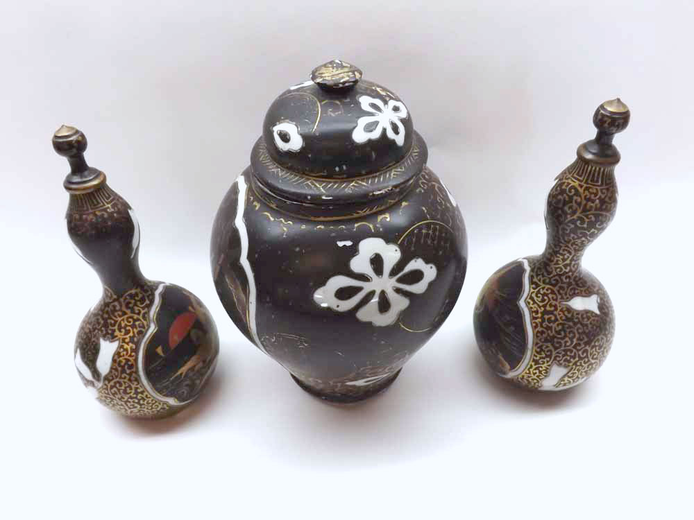 A Japanese famille noir composite Garniture, comprising a lidded jar and two similar covered