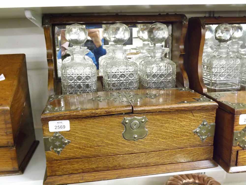 An early 20th Century Oak and Silver Plated Mounted Three Bottle Tantalus with mirror back over