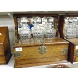 An early 20th Century Oak and Silver Plated Mounted Three Bottle Tantalus with mirror back over