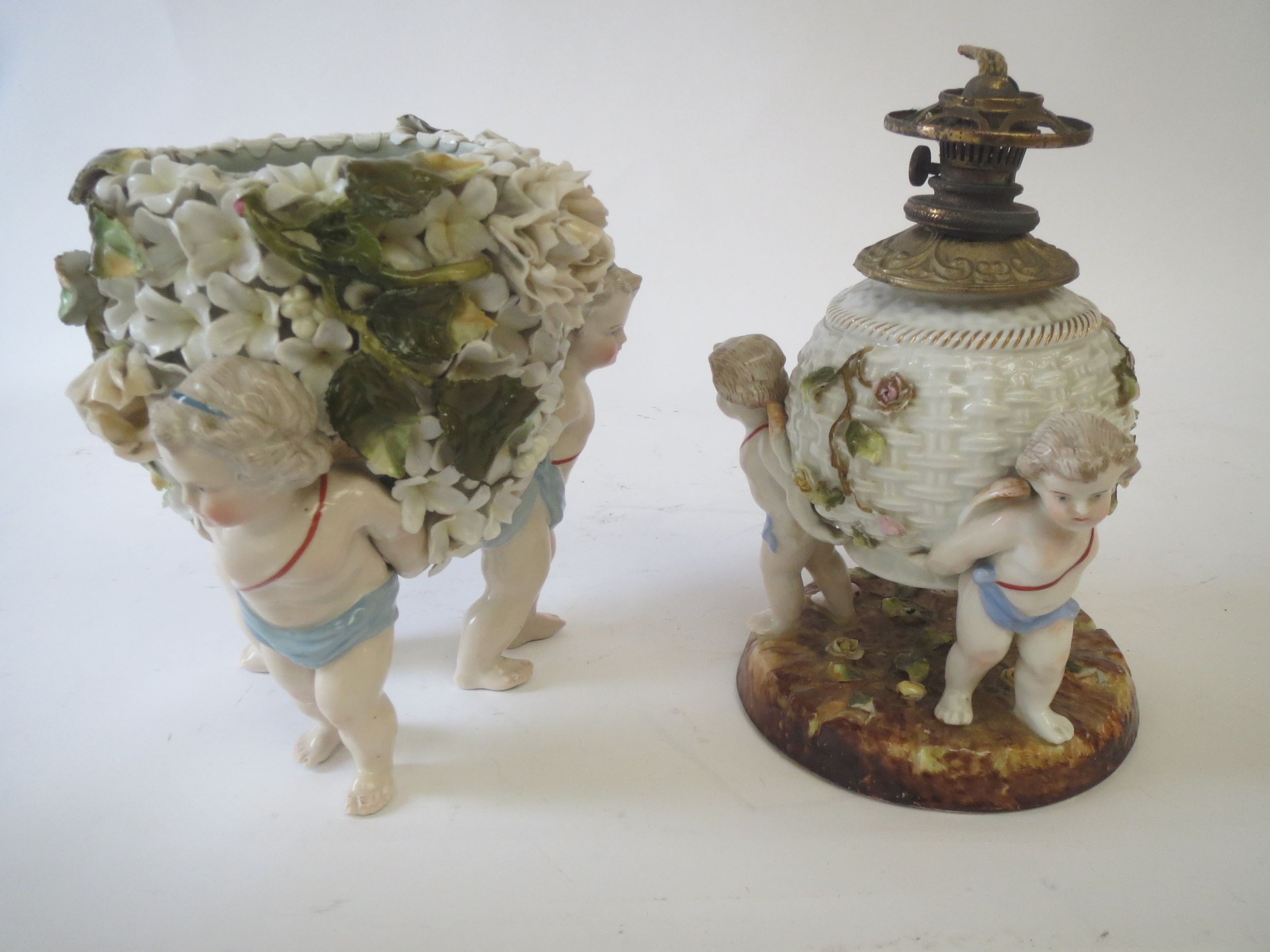 Continental encrusted floral porcelain cherub, a trio vase and a similar oil lamp Condition: very