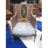 An Edwardian painted satinwood bergere with double caned sides, the back painted with flowers and