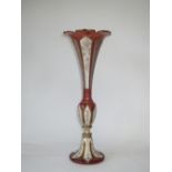 A late C19th Bohemian cranberry glass trumpet shaped vase with white overlay, highlighted in gilt on