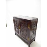 A Chinese carved hardwood two door cabinet with warriors and mythical dragon decoration in raised