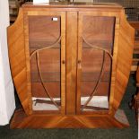 An Art Deco walnut two-door glazed display cabinet, the body of shield form with two shelves