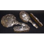 An Art Nouveau four-piece silver-mounted dressing set comprising a hand mirror, two brushes and a