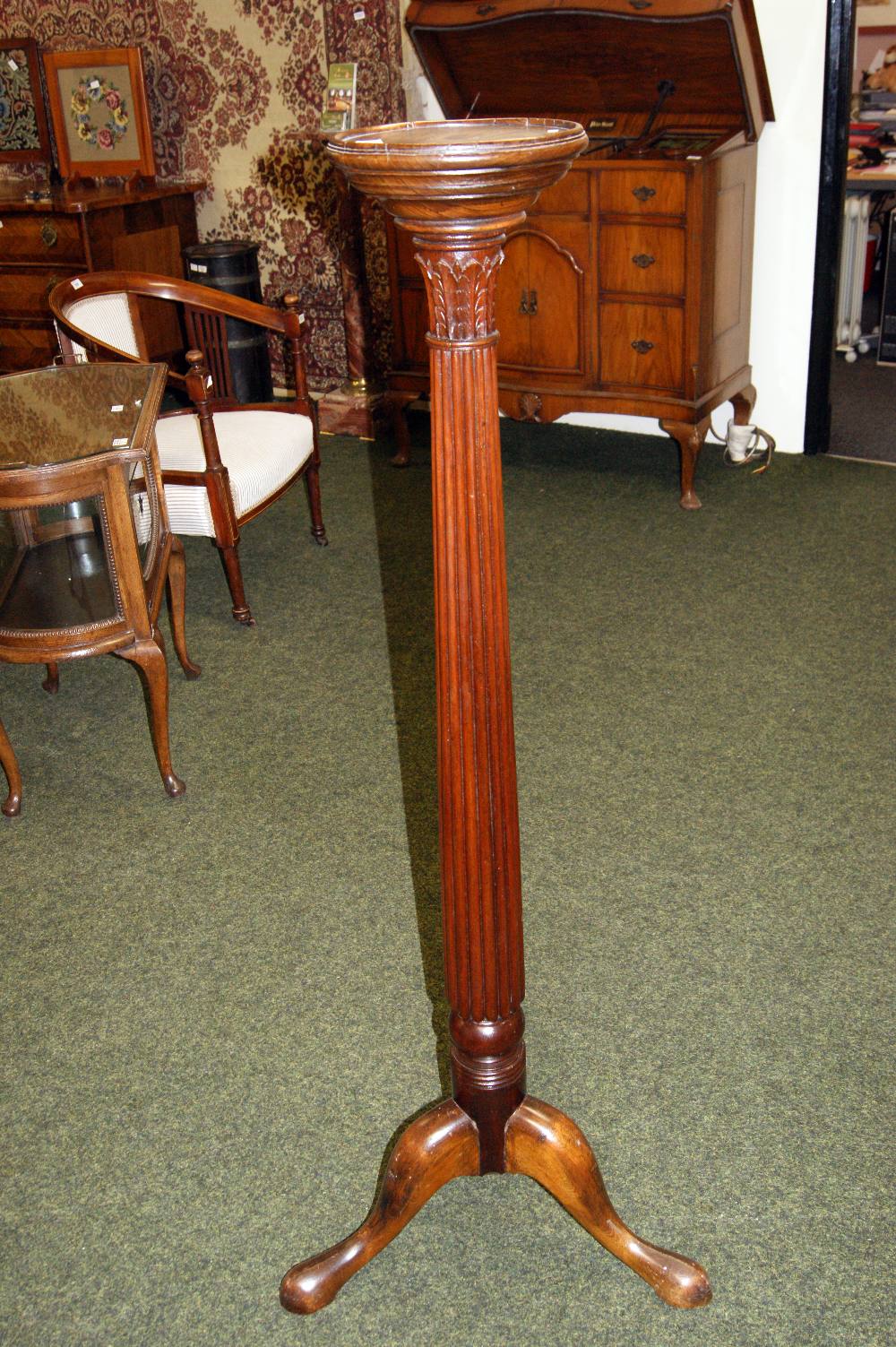 A Mahogany torchère stand, the column supported on a tripod base and having carved acanthus leaf