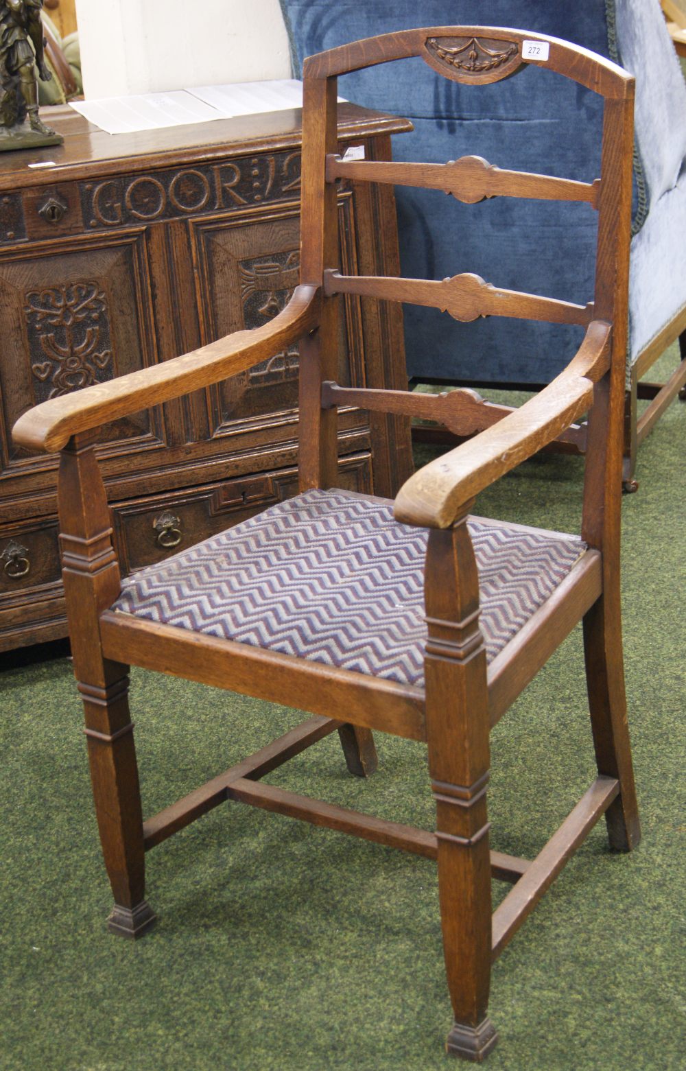 An arts and crafts gentleman's oak elbow chair with ladder back and upholstered pad seat.