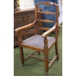 An arts and crafts gentleman's oak elbow chair with ladder back and upholstered pad seat.