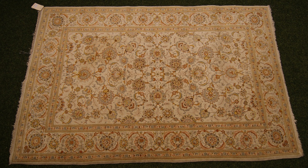 An Iranian floor rug with floral and geometric designs on a predominantly cream ground,