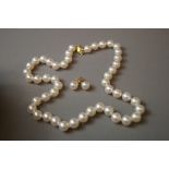 Single row of cultured pearls together with matching earrings