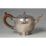 A George III silver bachelors teapot, of bullet shape, embossed with leaves and flowers, with walnut