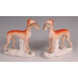 A pair of mid-Victorian Staffordshire hunting hounds, each modelled with a hare in its muzzle,